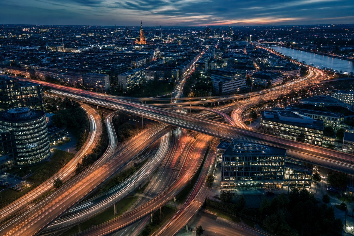 European smart city at dusk — highways with light trails and digital infrastructure